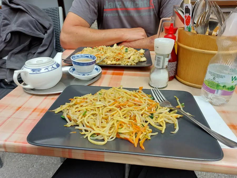 Gebratene Nudeln mit Ei und Karotten auf einem schwarzen Teller